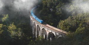 Nine Arches Bridge in Ella, Sri Lanka, with a train crossing over the iconic bridge surrounded by lush greenery.